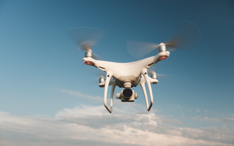 white-drone-hovering-bright-blue-sky